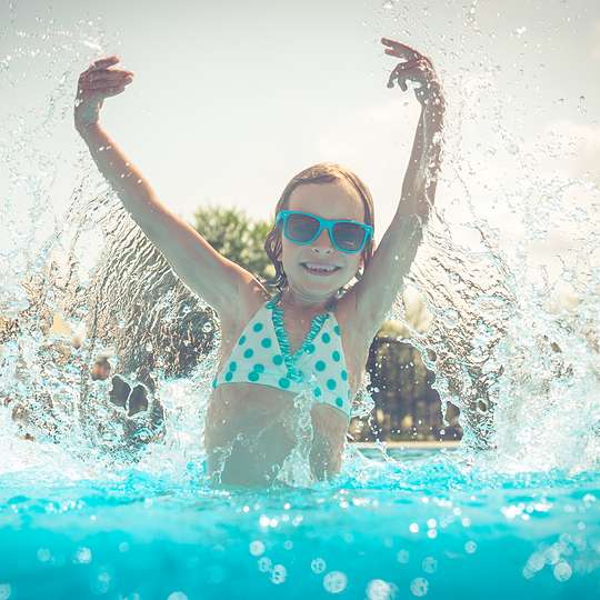 Child splashing water in swimming pool