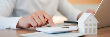 Person Using Calculator to calculate refinancing benefits