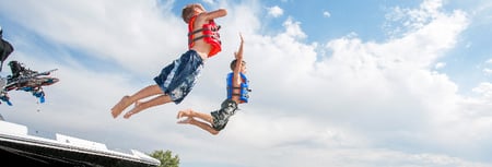 Boys jumping into lake from boat