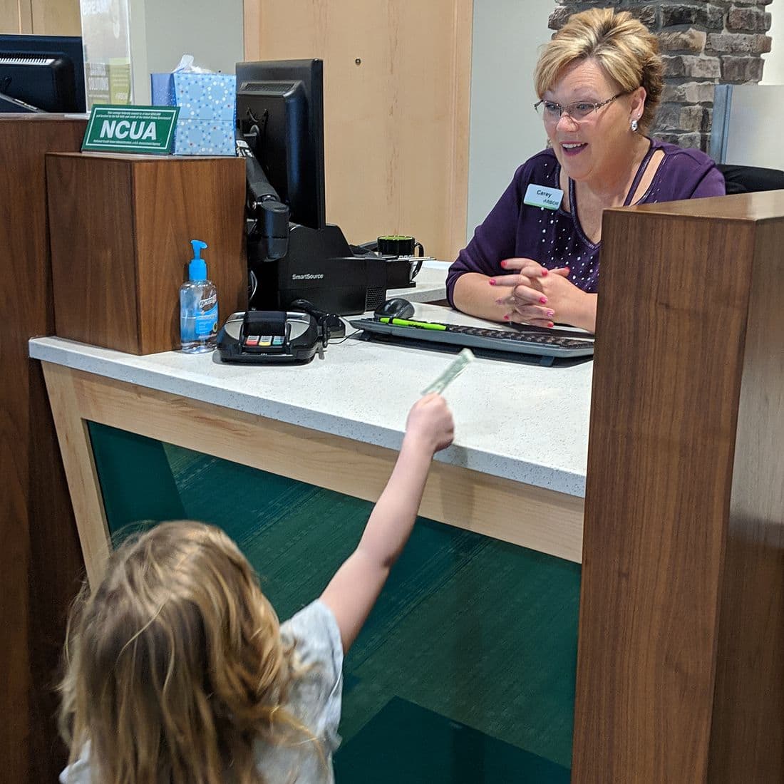 Child handing a bank teller money.