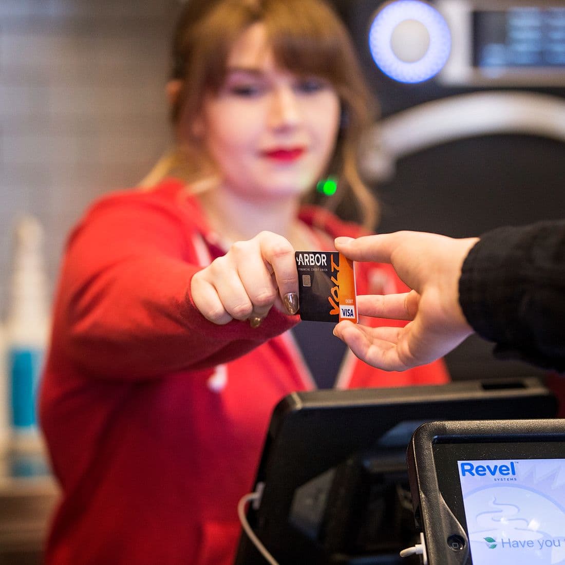 Arbor customer handing Volt Visa Card to cashier.