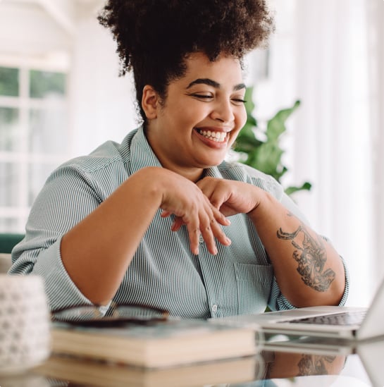 Arbor member smiling while using laptop at home.