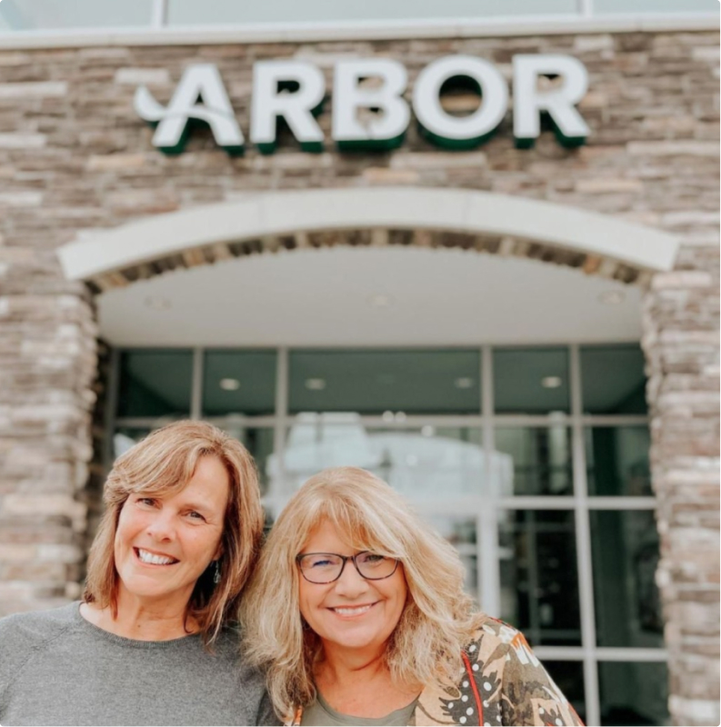 Two Arbor customers smiling in front of a location.