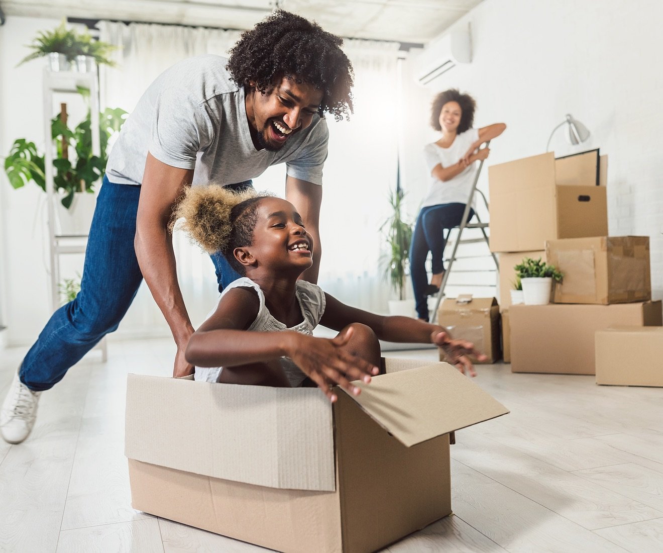 Father pushing daughter in moving box.