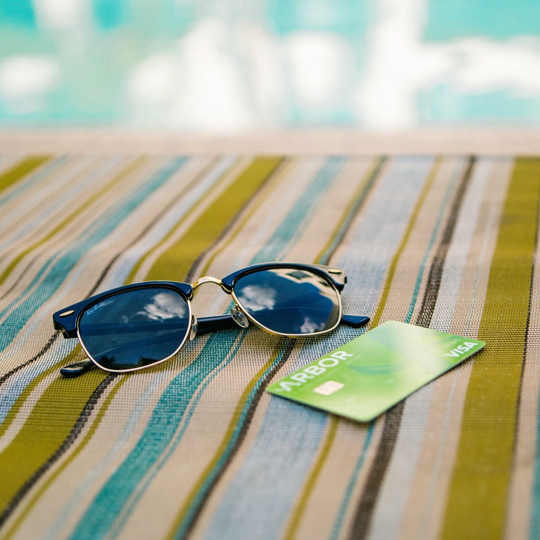 Sunglasses and an Arbor debit card on a beach towel.