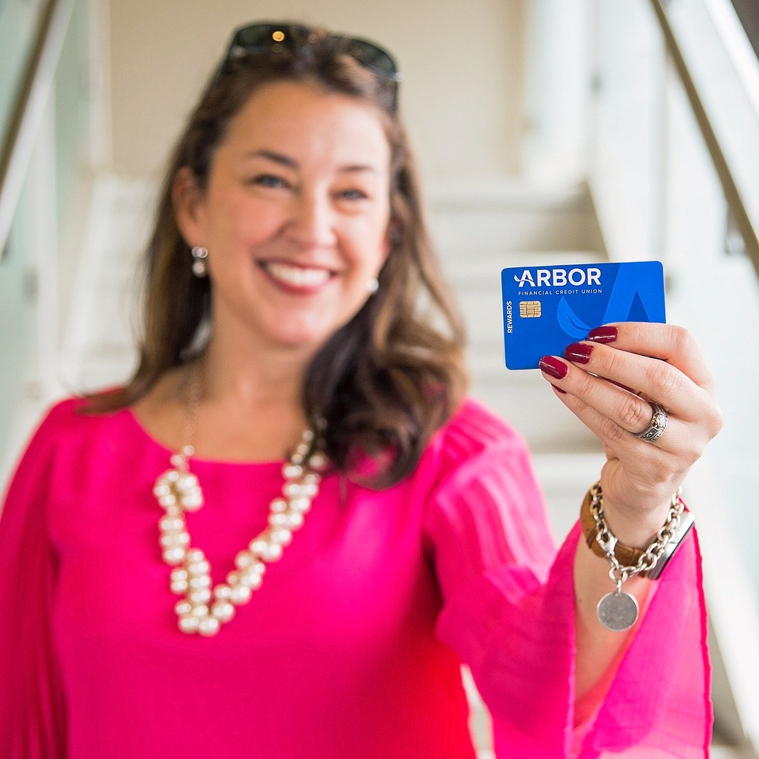A woman holding an Arbor Visa Rewards Credit Card.